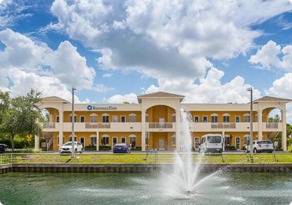 Lake with fountain in foreground of two story yellow building