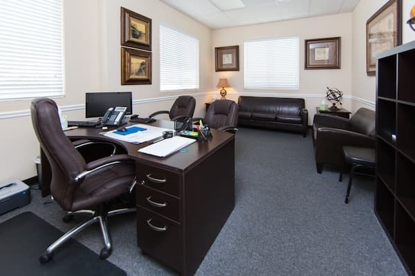 Office with large desk chair and leather sofas